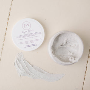 All natural Fresh Wife Baby Bums all natural diaper cream.  Container opened to show thick salve on a white background.